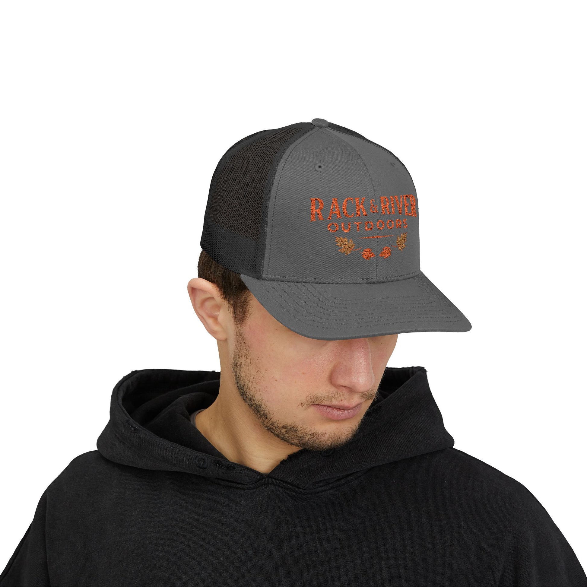 Male model in gray and black Rack & River Outdoors trucker cap with orange embroidered outdoor logo.